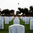 An image of a tombstone in a cemetery. The tombstone has the symbol for atheism on it where a religious symbol would normally be located.